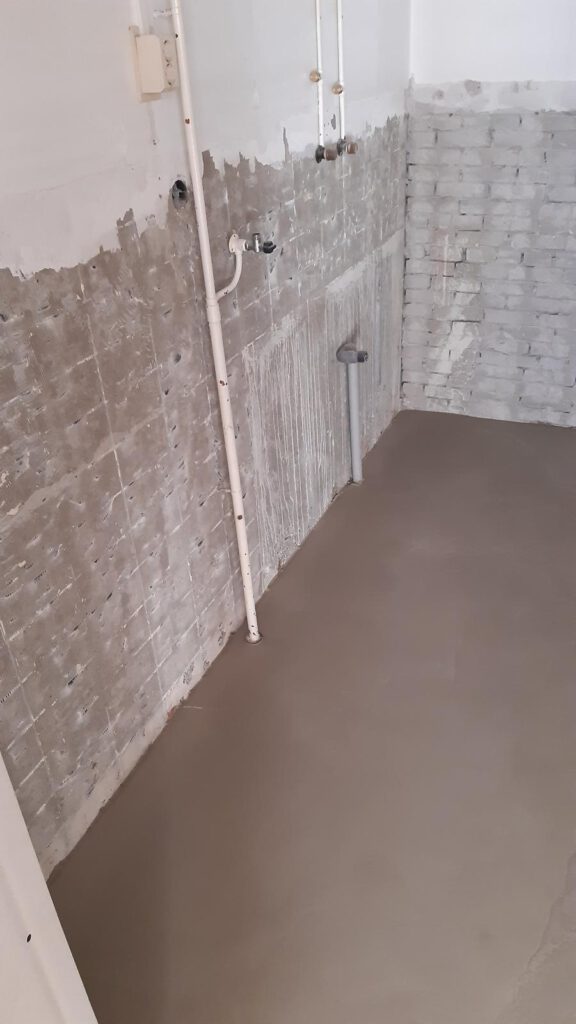 Voorbereide muur met egaliserende laag en geïnstalleerde leidingen door Elviservices.