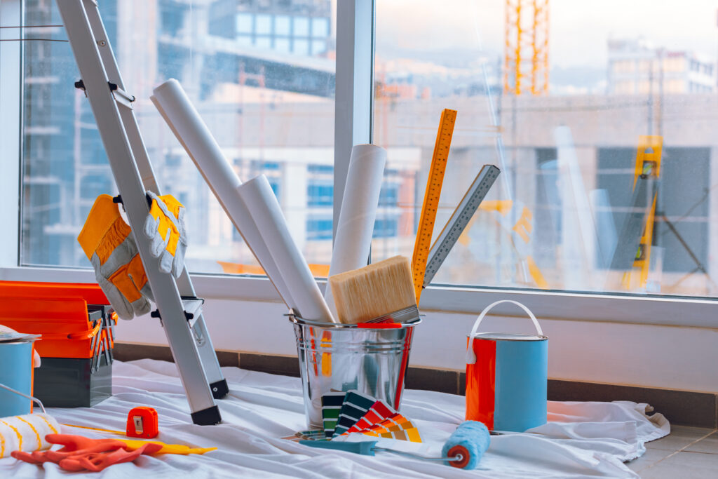 Schildergereedschap en materialen, zoals verfblikken, kwasten, en kleurstalen, klaar voor gebruik bij renovatiewerkzaamheden.