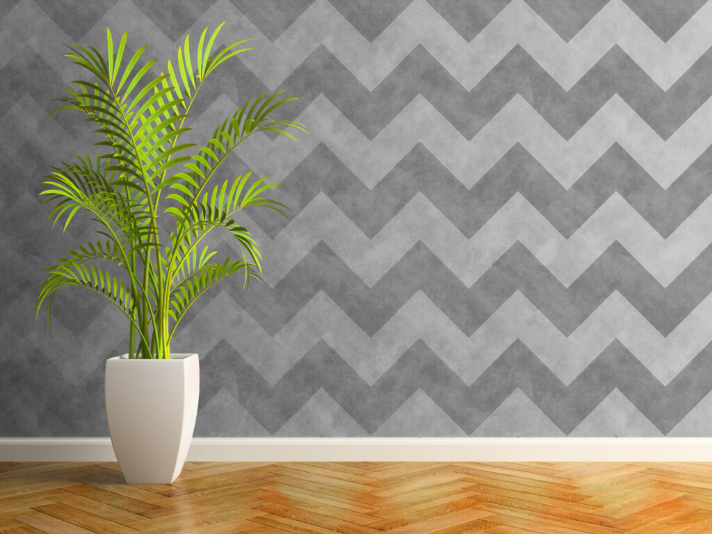 Modern grijs behang met een zigzagpatroon, gecombineerd met een houten vloer en een plant in een interieur.