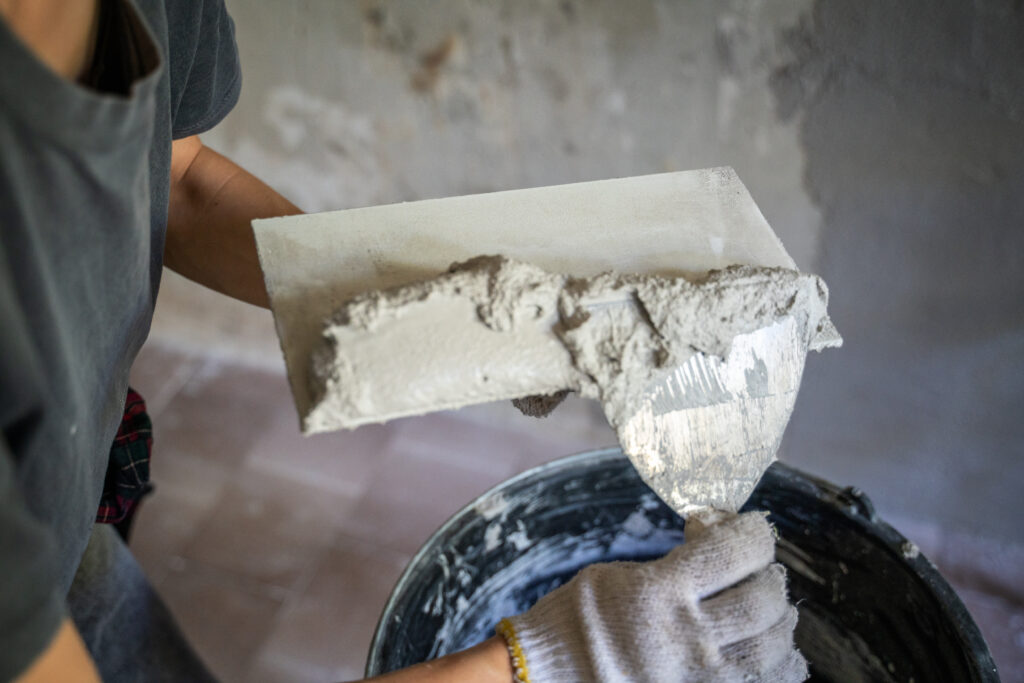 Stukadoor brengt pleister aan op een muur met een spaan tijdens renovatiewerkzaamheden.